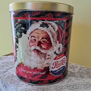 May include: A vintage metal tin with a Christmas theme featuring a depiction of Santa Claus and the text "Your good old friend". The tin is decorated with a red and green Pepsi-Cola logo and the words "Season's Greetings".