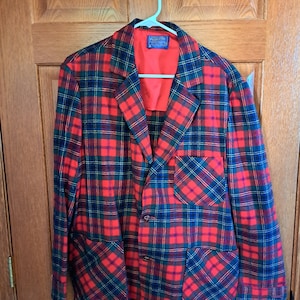May include: A red, green, and black plaid blazer with two button closures and two patch pockets. The label reads "Pennsville, Made in USA".