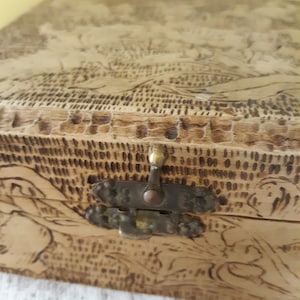 May include: A wooden box with a brass latch and a woodburned design of a landscape. The box is closed.