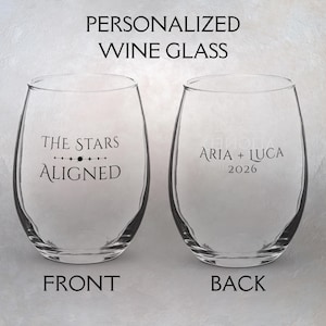 Könnte beinhalten: Zwei klare, stielose Weingläser. Ein Glas hat den Text "THE STARS ALIGNED" und das andere "ARIA + LUCA 2026". Der Text "PERSONALIZED WINE GLASS" steht oben, mit "FRONT" und "BACK" unten.