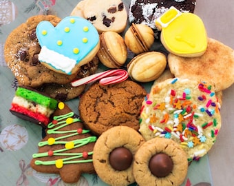 May include: A collection of assorted holiday cookies including a blue mitten-shaped sugar cookie, a yellow bell-shaped cookie, a green and red layered bar, a gingerbread tree with green icing, and round cookies with chocolate centers and sprinkles.