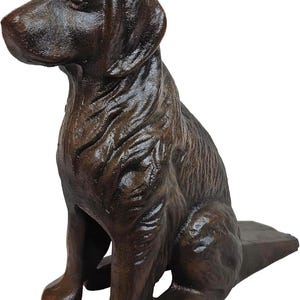 May include: A brown cast iron dog statue in a sitting position. The dog has a detailed textured coat and is posed with its head turned slightly to the left. The statue is a decorative item.