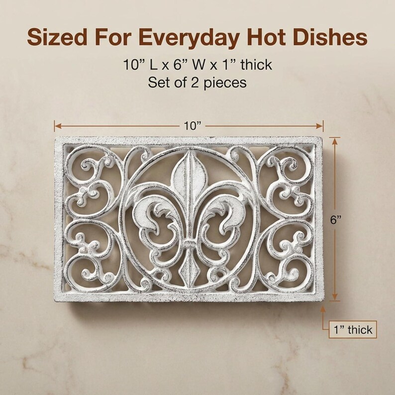 May include: White rectangular trivet with an ornate fleur-de-lis design. The trivet is 10 inches long, 6 inches wide, and 1 inch thick. The text "Sized For Everyday Hot Dishes" is at the top. Set of 2 pieces.