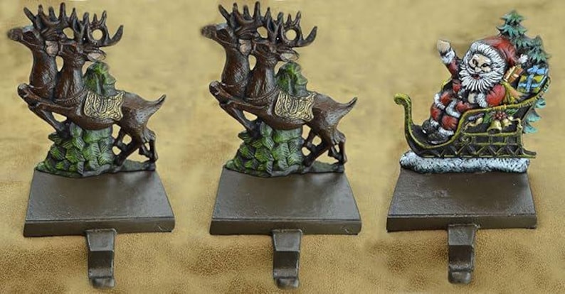May include: Three Christmas stocking holders. Two feature brown reindeer with green foliage, and one depicts Santa Claus in a sleigh. All have a brown base with a hook for hanging stockings. The reindeer holders have gold accents.
