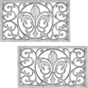 May include: Two rectangular, cast iron doormats with a distressed white finish. Each mat features a central fleur-de-lis design within a circular frame, surrounded by ornate scrollwork. The mats are designed for outdoor use.