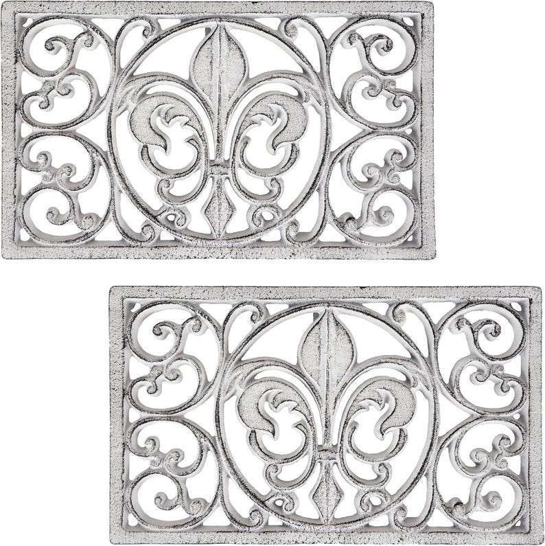 May include: Two rectangular, cast iron doormats with a distressed white finish. Each mat features a central fleur-de-lis design within a circular frame, surrounded by ornate scrollwork. The mats are designed for outdoor use.