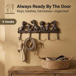 May include: A dark brown metal wall-mounted key and leash holder with five hooks. The holder features a decorative design of five dog figures. The text "Always Ready By The Door" and "Keys, leashes, harnesses—organized" is visible.