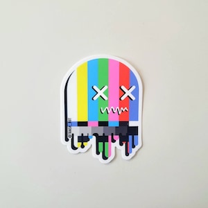 May include: A sticker of a melting TV static screen with a face. The face has two X's for eyes and a wavy line for a mouth. The sticker is white with a colorful TV static screen inside. The text '@TRASH_BOT' is on the side of the sticker.
