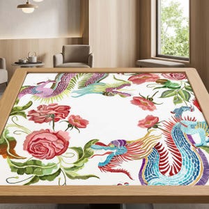 May include: A square table featuring a white surface decorated with a vibrant pattern of colorful dragons and large pink roses. The dragons are rendered in shades of blue, purple, and red, while the roses are depicted with green leaves.