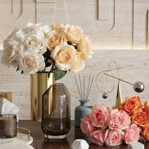 May include: A display of home decor items including bouquets of white, peach, and orange roses in gold and glass vases. A candle, decorative objects, and a diffuser are also present, creating an elegant and stylish arrangement.