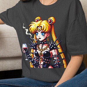 Könnte beinhalten: Ein dunkelgraues T-Shirt mit einem Grafikdruck einer blonden Anime-Figur mit blauen Augen, die ein schwarzes Outfit mit Stacheln trägt, ein Glas Rotwein hält und eine Zigarette raucht. Die Figur hat langes blondes Haar in zwei Knoten.