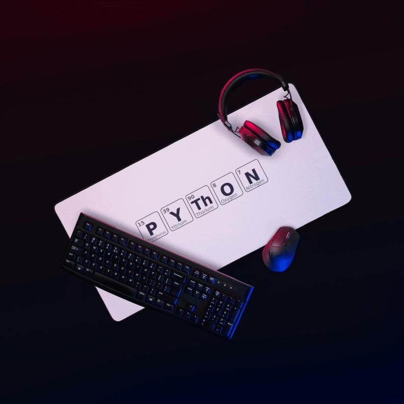 以下が含まれることがあります： 周期表の元素を使って「PYTHON」という単語が書かれた白い長方形のマウスパッド。黒いキーボード、ワイヤレスマウス、ヘッドフォンも表示されています。アイテムは、赤と青の照明を備えた暗い背景に設定されています。
