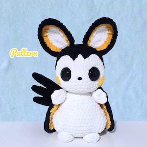 May include: A handmade crochet plush toy in the shape of a bat-like creature. The toy is primarily white with black accents on the ears, wings, and around the eyes. Yellow details are present on the ears and cheeks. The word "Pattern" is written on the top left.