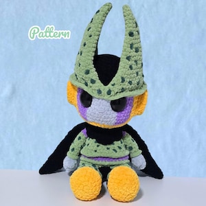 Puede incluir: Una muñeca de ganchillo hecha a mano de un personaje con una combinación de colores verde y negro. La muñeca tiene ojos negros grandes, una cara morada y gris y orejas amarillas. La muñeca lleva un atuendo verde con rayas moradas y tiene pies amarillos grandes. La palabra "Pattern" está en la imagen.