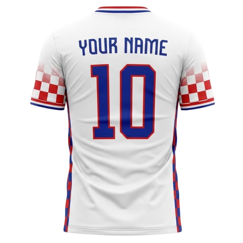 May include: White soccer jersey with blue and red accents. The jersey features the number 10 in blue, with the text "YOUR NAME" above it. The sleeves have a red and white checkered pattern.