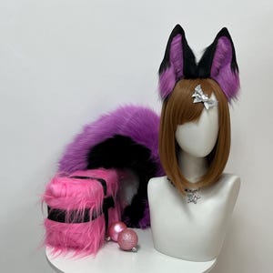 May include: A cosplay set featuring a purple and black faux fur tail, pink and black striped leg warmers, and matching fox ears with purple and black accents. A mannequin head wears a brown wig and a star necklace.