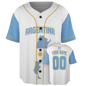 May include: A white baseball jersey with light blue sleeves and gold trim. The front features the word ARGENTINA in light blue letters above a map of Argentina with the national flag design. The back displays the text YOUR NAME and the number 00.