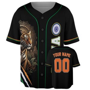 Pode incluir: Uma camisola de basebol preta com um gráfico de tigre, um emblema circular e debrum verde. A frente apresenta um tigre num cenário de selva com elementos arquitetónicos. As costas mostram o texto YOUR NAME e o número 00 em cor de laranja.