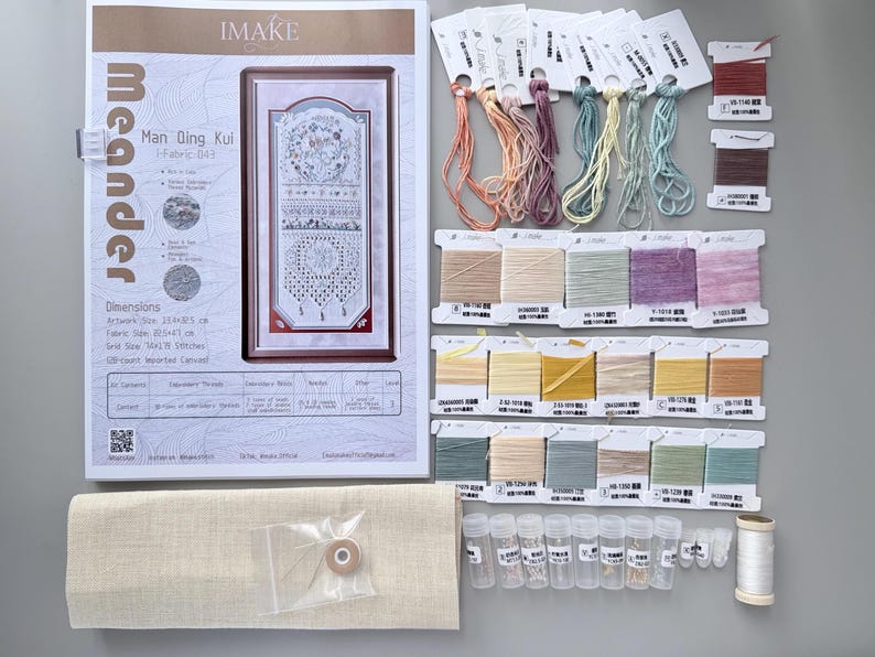 May include: A cross-stitch kit featuring an instruction booklet with the text Meander Man Qing Kui, a piece of beige fabric, numerous skeins of embroidery thread in pastel shades, small plastic vials containing beads, and a spool of white thread.