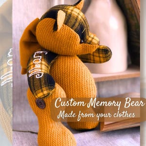 Peut inclure: Un ours en peluche fait à la main à partir de vêtements, avec un motif à carreaux jaune et noir sur les oreilles et les pattes. L'ours porte le mot "Mom" brodé sur un bras. Le texte "Custom Memory Bear Made from your clothes" est également visible.