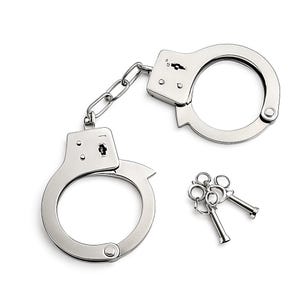 Puede incluir: Unas esposas plateadas brillantes con una cadena de conexión y dos llaves. Las esposas son de metal y tienen un diseño clásico. Las llaves son pequeñas y tienen un anillo para sujetarlas. Los artículos están sobre un fondo blanco.