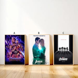 Może przedstawiać: Trzy oprawione plakaty filmowe z filmu "Avengers: Endgame". Plakaty są w drewnianych ramach i przedstawiają różne kompozycje postaci i sceny. Plakaty mają tytuł filmu i datę premiery.