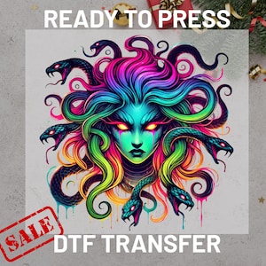 May include: A colorful DTF transfer featuring a Medusa design. The artwork showcases a woman's face with vibrant green skin, fiery eyes, and a head of snakes in shades of blue, pink, and green. The words "READY TO PRESS" and "SALE" are also visible.
