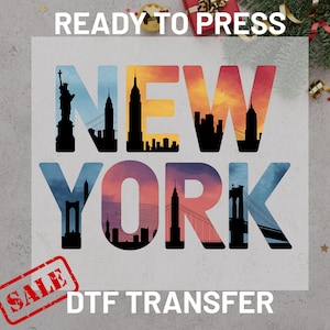 May include: A DTF transfer featuring the text "NEW YORK" in colorful gradient letters, with iconic city skyline silhouettes filling each letter. The word "SALE" is stamped in a red rectangle. The words "READY TO PRESS" are at the top.
