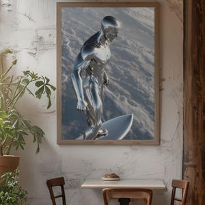 May include: A framed print featuring a chrome-like figure surfing on a silver surfboard. The artwork is set against a backdrop of a cloudy, textured surface. The print is displayed on a white wall, with a table and chairs in front.
