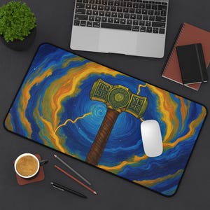 May include: A rectangular mousepad featuring a stylized illustration of Thor's hammer, Mjolnir, set against a swirling blue and gold background. The design resembles a starry night sky with lightning bolts. A white computer mouse rests on the pad.
