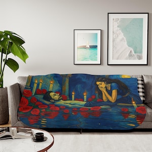 Op de afbeelding: Een sprei met een schilderij van een persoon in water, omringd door rode rozen en kaarsen. Een vrouw in een blauwe jurk zit in de buurt. Het kunstwerk gebruikt blauwe, gele en rode tinten.