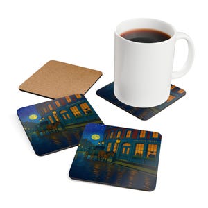 Könnte beinhalten: Eine weiße Kaffeetasse steht auf einem Untersetzer mit einer nächtlichen Straßenszene. Der Untersetzer zeigt ein Gebäude mit beleuchteten Fenstern, eine Pferdekutsche und den Text "221B BAKER STREET". Weitere Untersetzer und ein Korkuntersetzer sind ebenfalls zu sehen.
