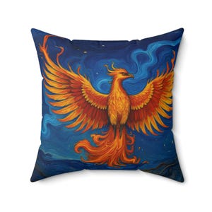 Könnte beinhalten: Quadratisches Kissen mit einem lebendigen Phönix-Design. Das Kunstwerk zeigt den mythischen Vogel mit ausgebreiteten Flügeln in Orange- und Gelbtönen vor einem tiefblauen Hintergrund. Das Kissen ist ein dekoratives Wohnaccessoire.