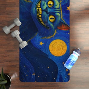 May include: A blue yoga mat with a grinning cat illustration, yellow eyes and teeth, against a starry night sky and a yellow moon. Two grey dumbbells and a blue water bottle are next to the mat.
