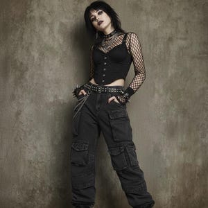 Op de afbeelding: Zwart korsettopje met een shirt met lange mouwen van visnet, gecombineerd met een zwarte cargobroek en combat boots. De outfit is geaccessoireerd met een riem met studs, een choker en polsbandjes. De algehele stijl is goth en edgy.
