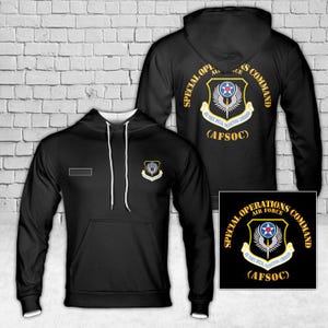 May include: Black hoodie with white drawstrings and a front pocket. The hoodie features a patch on the chest and a larger design on the back, both displaying the text "SPECIAL OPERATIONS AIR FORCE COMMAND (AFSOC)" in gold and white.