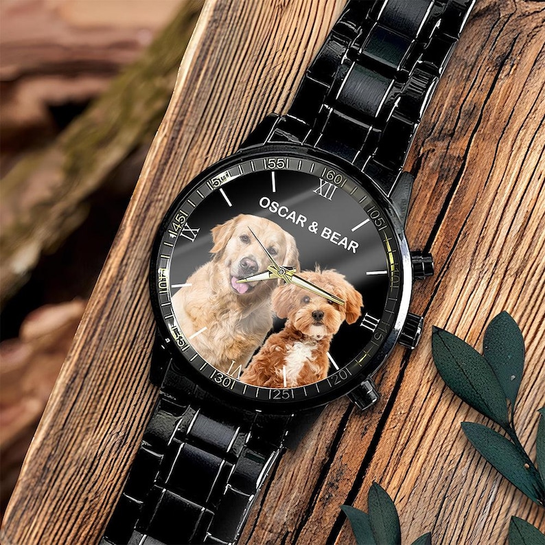 May include: A black metal wristwatch featuring a round face with a photographic print of a golden retriever and a smaller brown dog. The dial displays the text OSCAR & BEAR in white, with gold-toned hour, minute, and second hands on a black background.