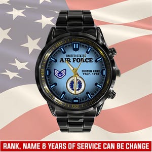 May include: A black stainless steel wristwatch with a blue gradient dial featuring the United States Air Force logo, a rank insignia, and customisable text including "UNITED STATES AIR FORCE", "CUSTOM NAME", and the years "1967 - 1978".