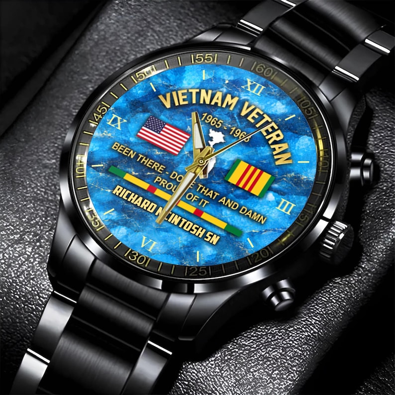May include: Black wristwatch with a blue face featuring the text "Vietnam Veteran 1965-1966". The watch face includes the American and South Vietnamese flags. The watch band and case are black.