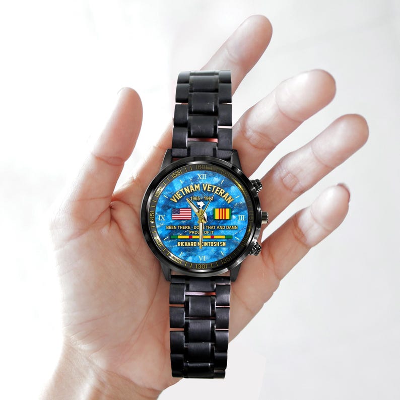 May include: Black wristwatch with a blue face featuring the text "Vietnam Veteran 1965-1968". The watch face includes the American and Vietnamese flags. The watch band is black.