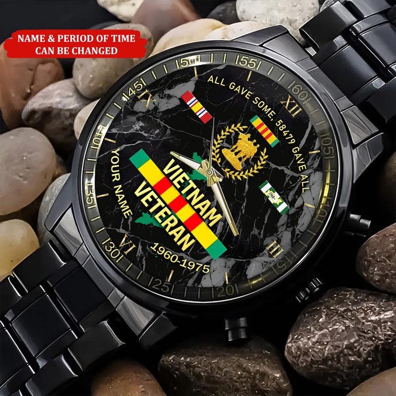 May include: Black wristwatch with a marble-effect face, featuring the words "Vietnam Veteran" and the years "1960-1975." The watch face includes military emblems and the text "All Gave Some, 58479 Gave All." The watch has a black metal band.
