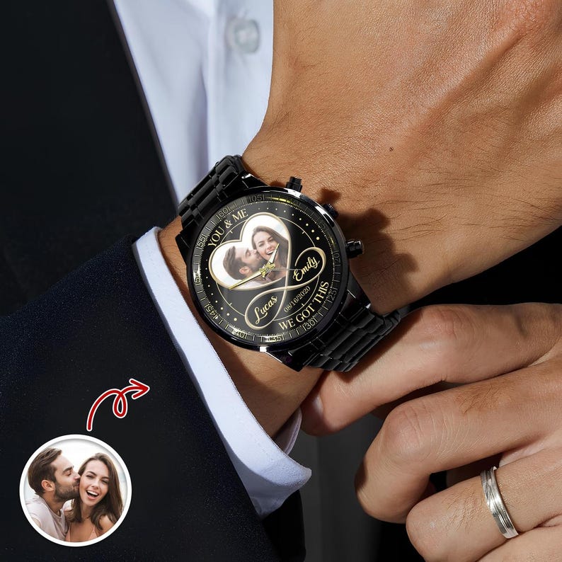 May include: A black metal wristwatch with a circular face featuring a custom photo of a couple inside an infinity symbol. The watch dial includes the text YOU & ME, Emily, Lucas, 08/16/2020, and WE GOT THIS, with a black link bracelet band.