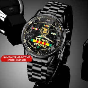 May include: Black wristwatch with a checkered band and a round face. The watch face features the text "Vietnam Veteran" and the years "1960-1975". The watch also has the text "All gave some, 58479 gave all".