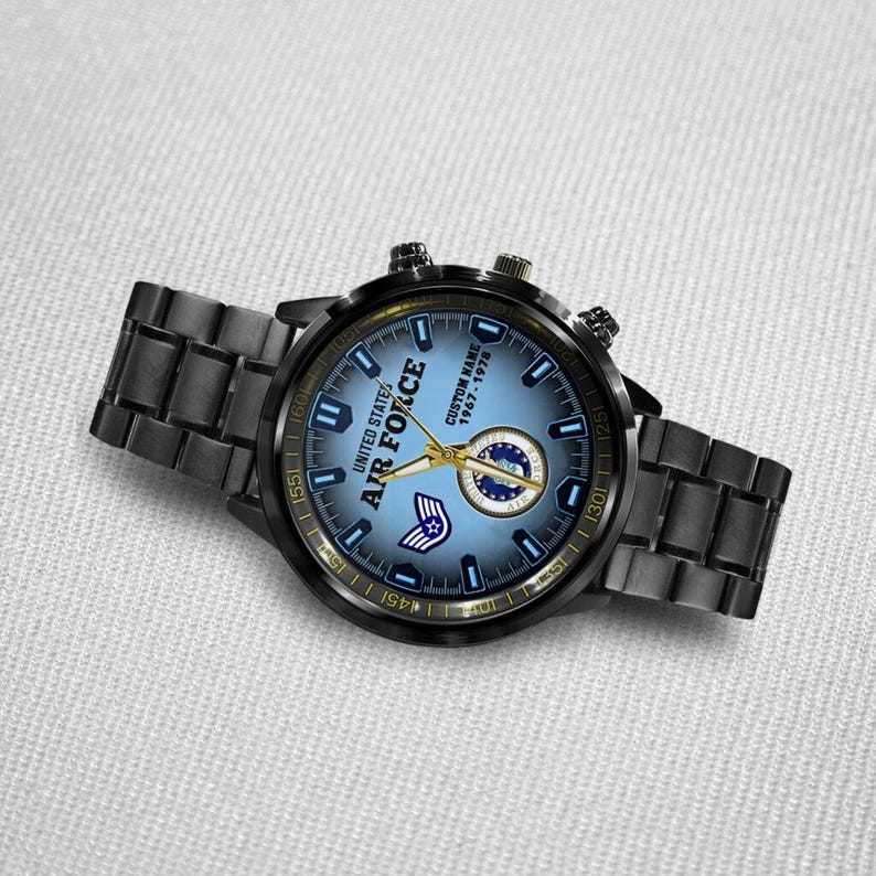 May include: A black metal wristwatch with a blue gradient dial featuring the text UNITED STATES AIR FORCE, CUSTOM NAME, and 1967-1978. The watch includes gold-toned hands, a circular emblem, and a small wing icon on the face with a link bracelet.
