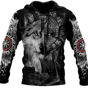 May include: Black zip-up hoodie featuring a detailed wolf face design split down the middle. One side shows a realistic wolf, the other a Viking-inspired graphic. Sleeves have red and white Celtic knotwork and symbols. A hooded sweatshirt.