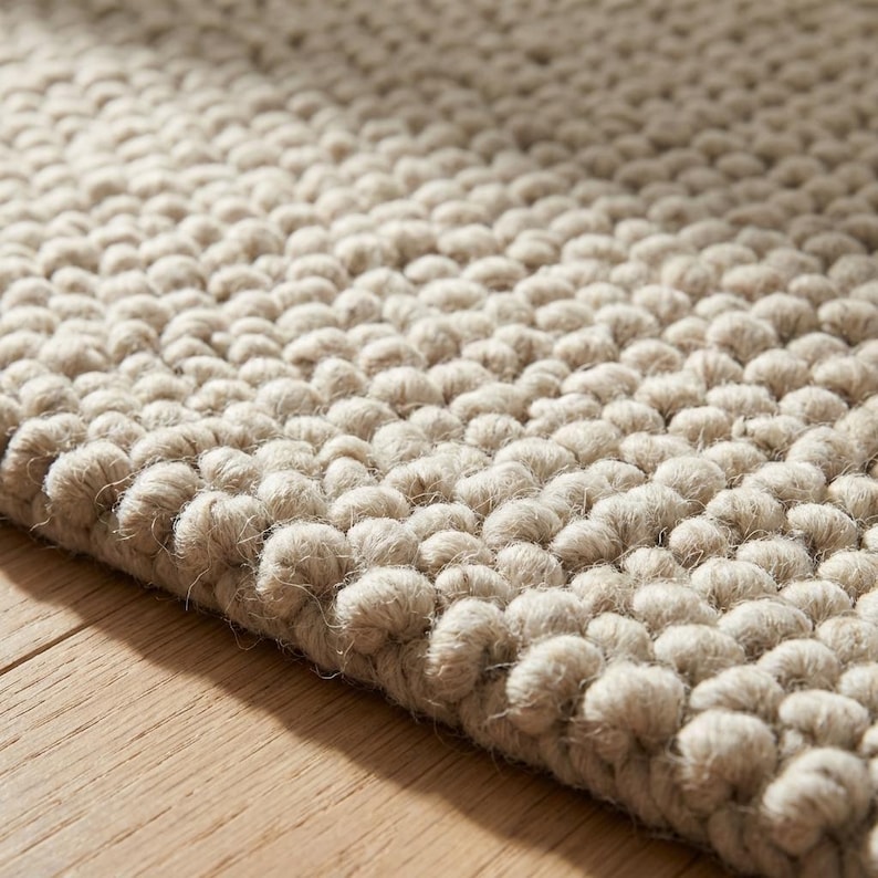 Close up of textured wool area rug featuring chunky loops and natural fibers in soft neutral shades