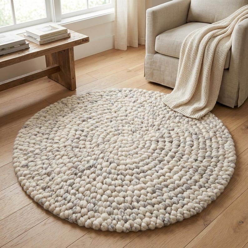 Puede incluir: Una alfombra redonda de color blanquecino con un dise&ntilde;o texturizado y en bucle. La alfombra est&aacute; colocada sobre un suelo de madera, y sus tonos neutros complementan la decoraci&oacute;n de la habitaci&oacute;n. El di&aacute;metro de la alfombra es de aproximadamente 152 cm.