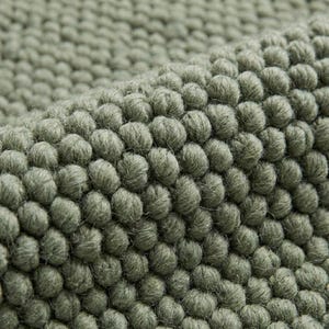 Close-up of chunky wool rug showing thick knitted wool fibers, natural handmade rug for rustic and modern homes