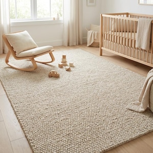 May include: A neutral-toned, textured area rug in a nursery setting. The rug is made of a thick, woven material. A wooden rocking chair with a cream-colored cushion and a wooden crib are also in the room. Wooden toys are scattered on the rug.