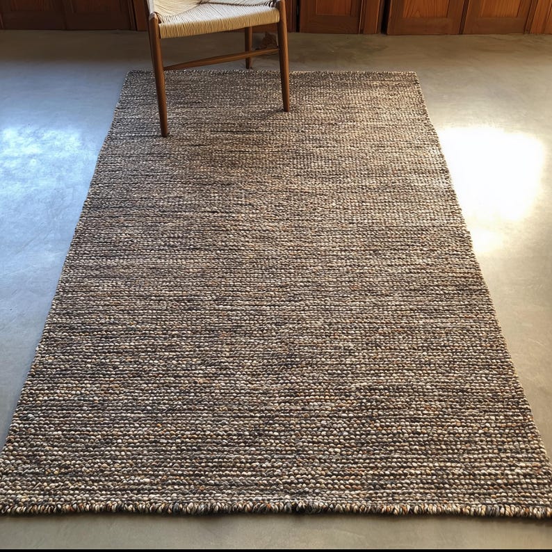 Textured wool rug with dense woven pattern in warm neutrals, modern minimalist home décor floor rug under wooden chair.